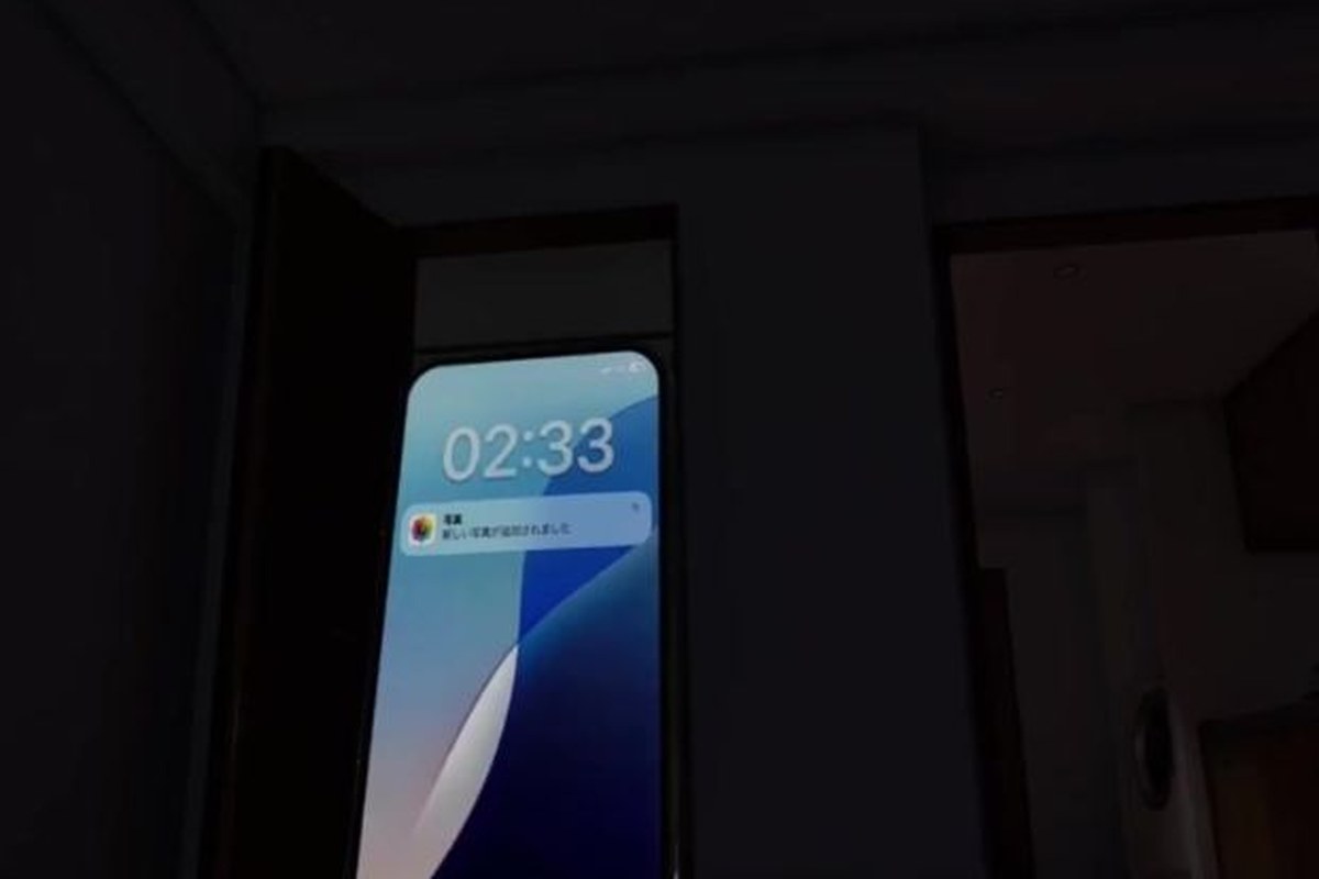 事故物件 2:33 AM - 暗い部屋で 02:33 を表示し、写真の追加通知が届いたスマートフォン | PIXEL PROMO